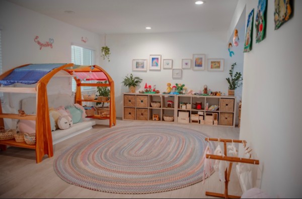 A cozy corner of the playroom with a canopy nap nook, toy cubbies, and framed children's artwork