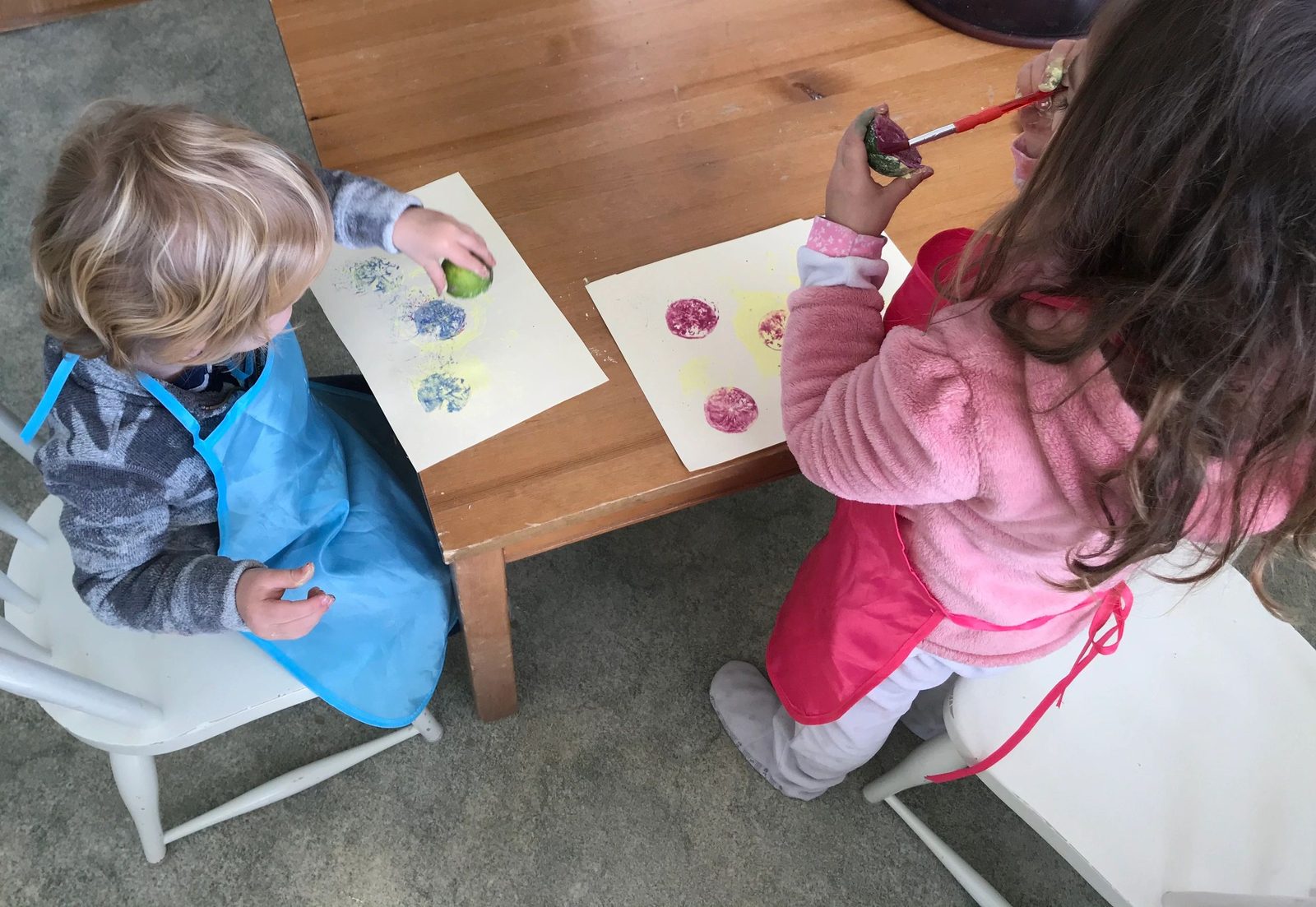 Two children painting with fruit stamps