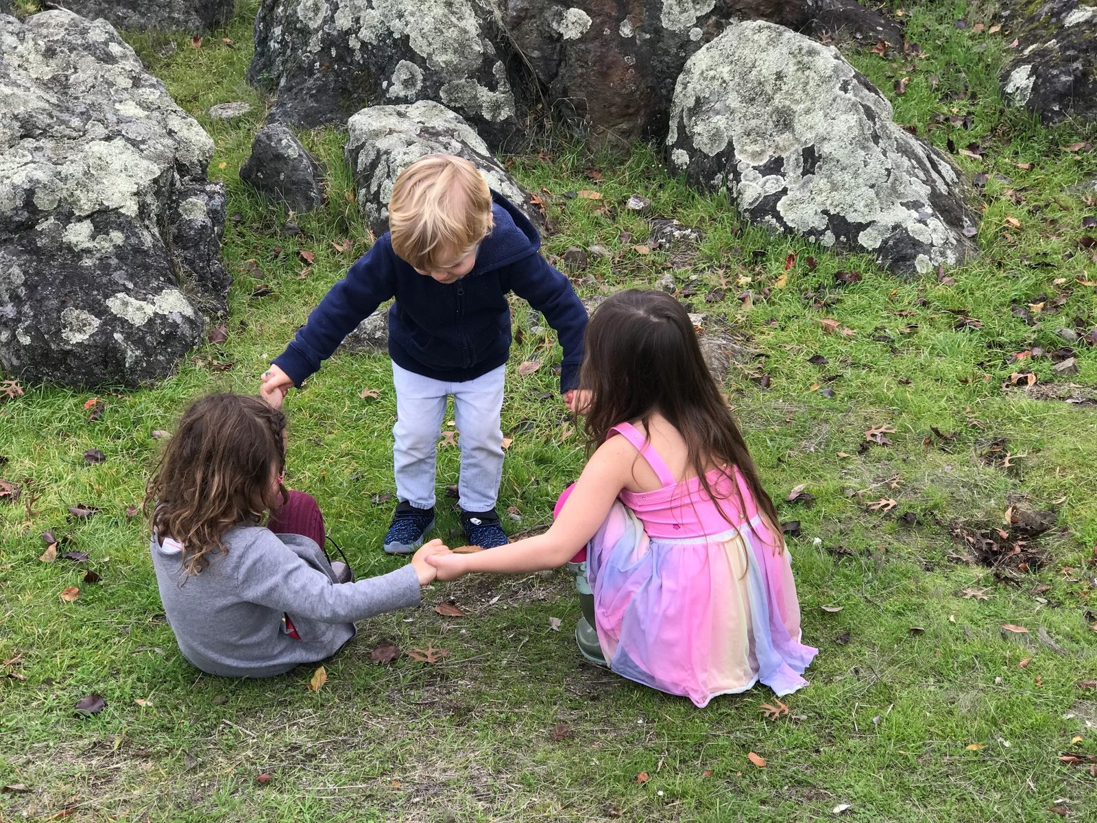 Children sitting together outdoors on rocks