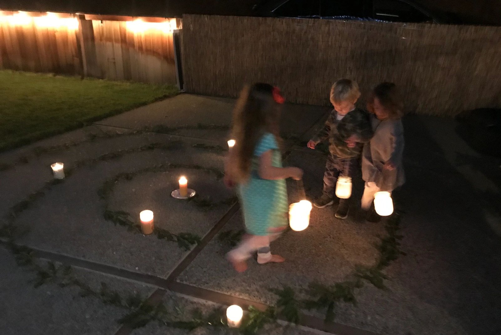 Children walking a candlelit lantern spiral at night