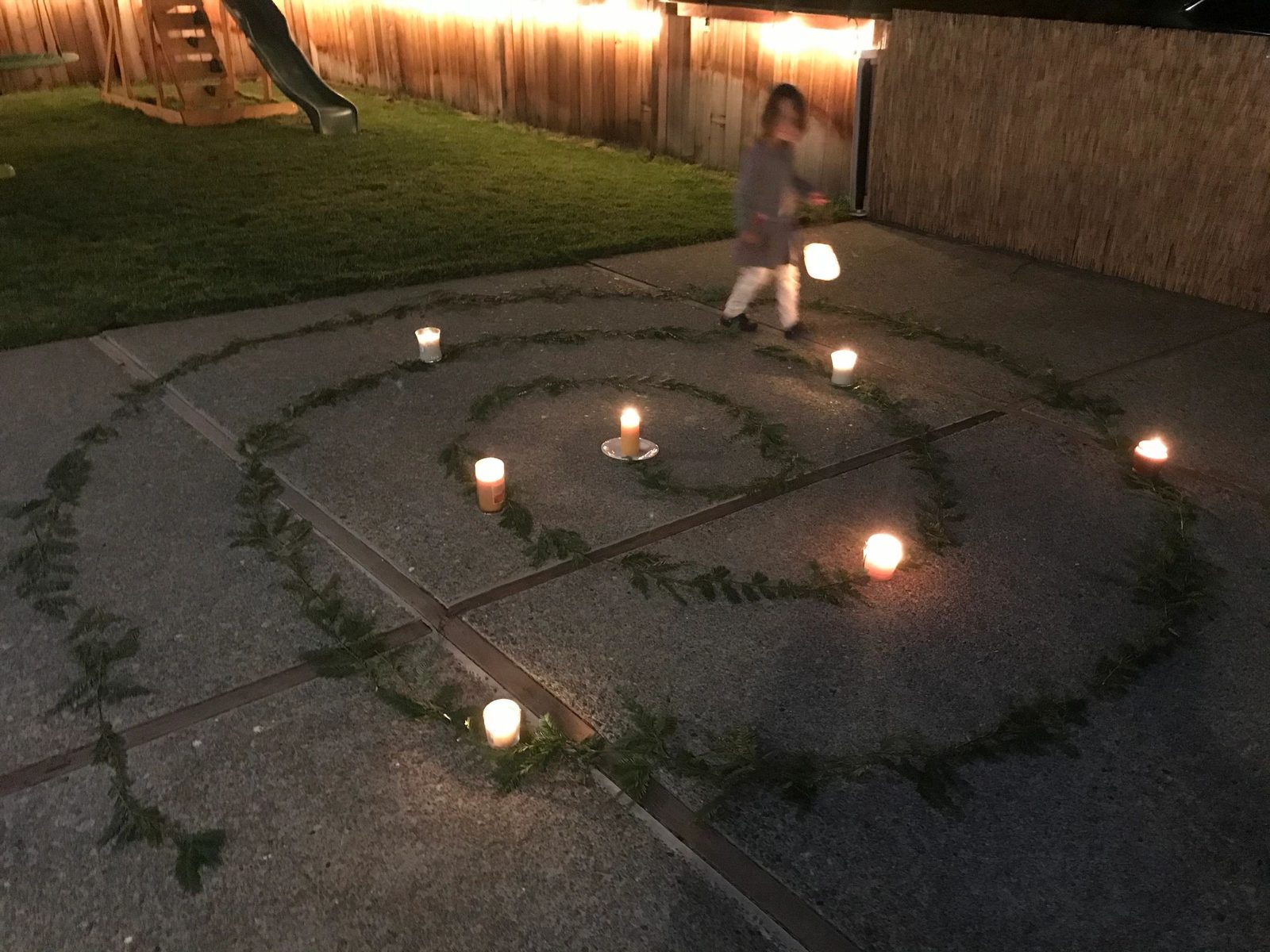 Children on an evening lantern walk around a candlelit spiral