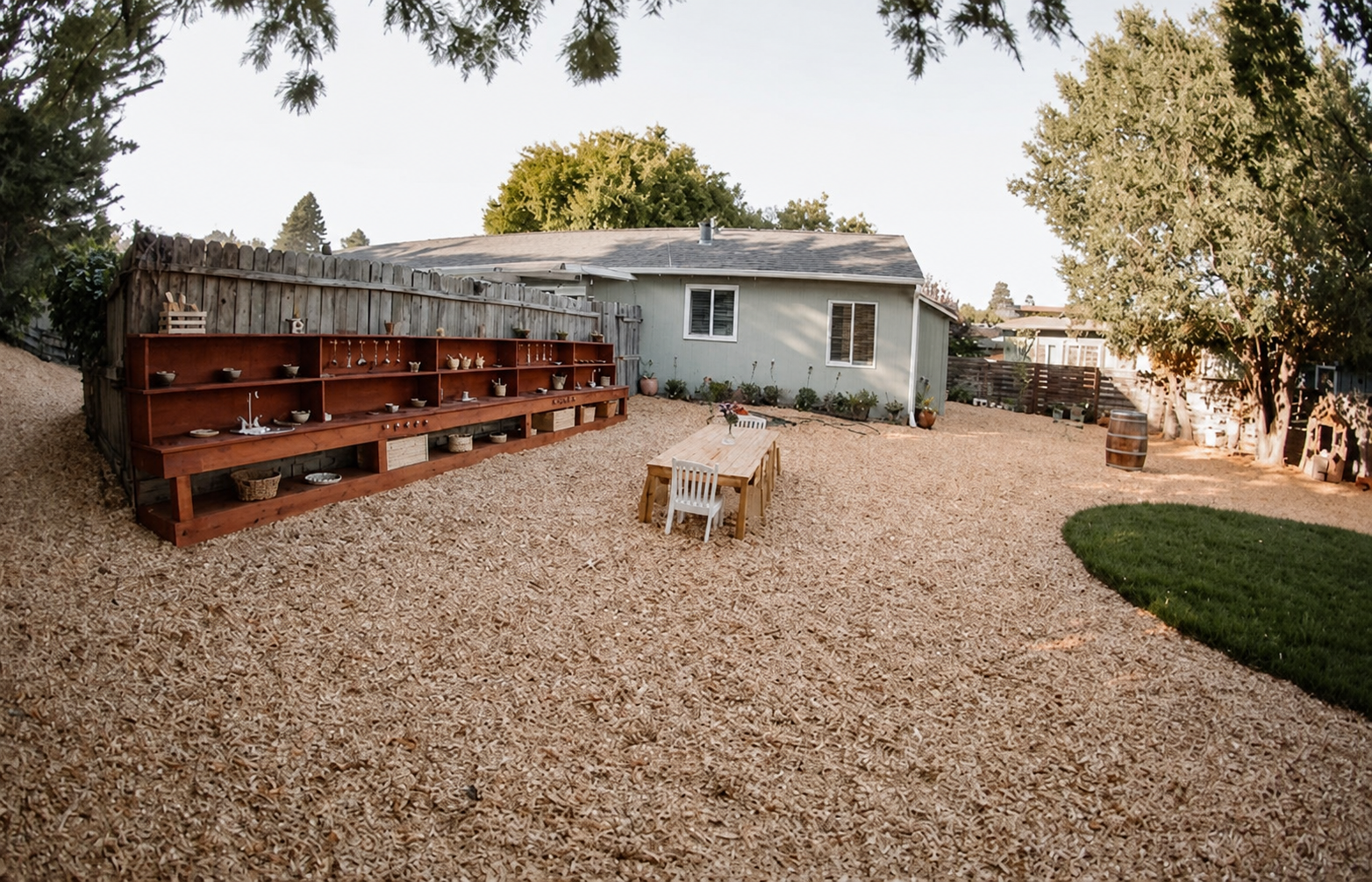 The outdoor mud kitchen shelf and a child-sized table in the yard