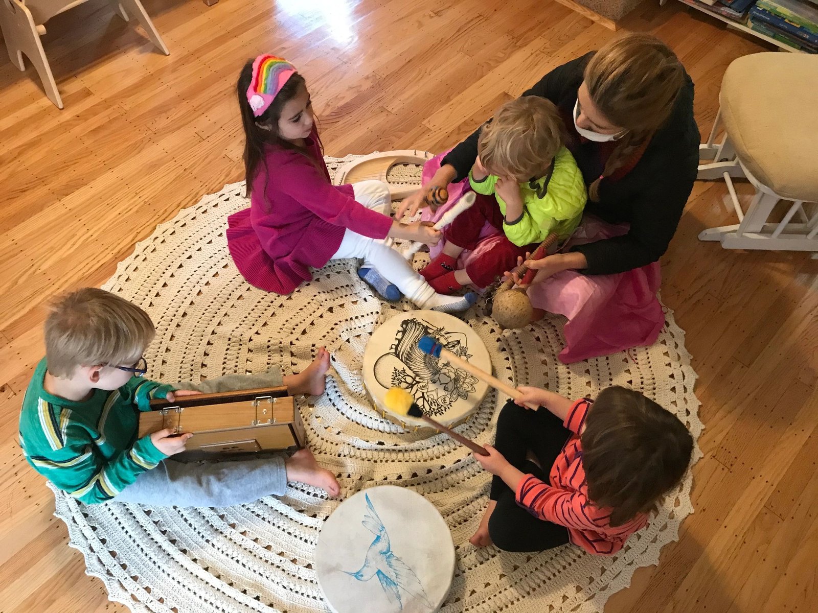 Children and their teacher making music together on a round rug