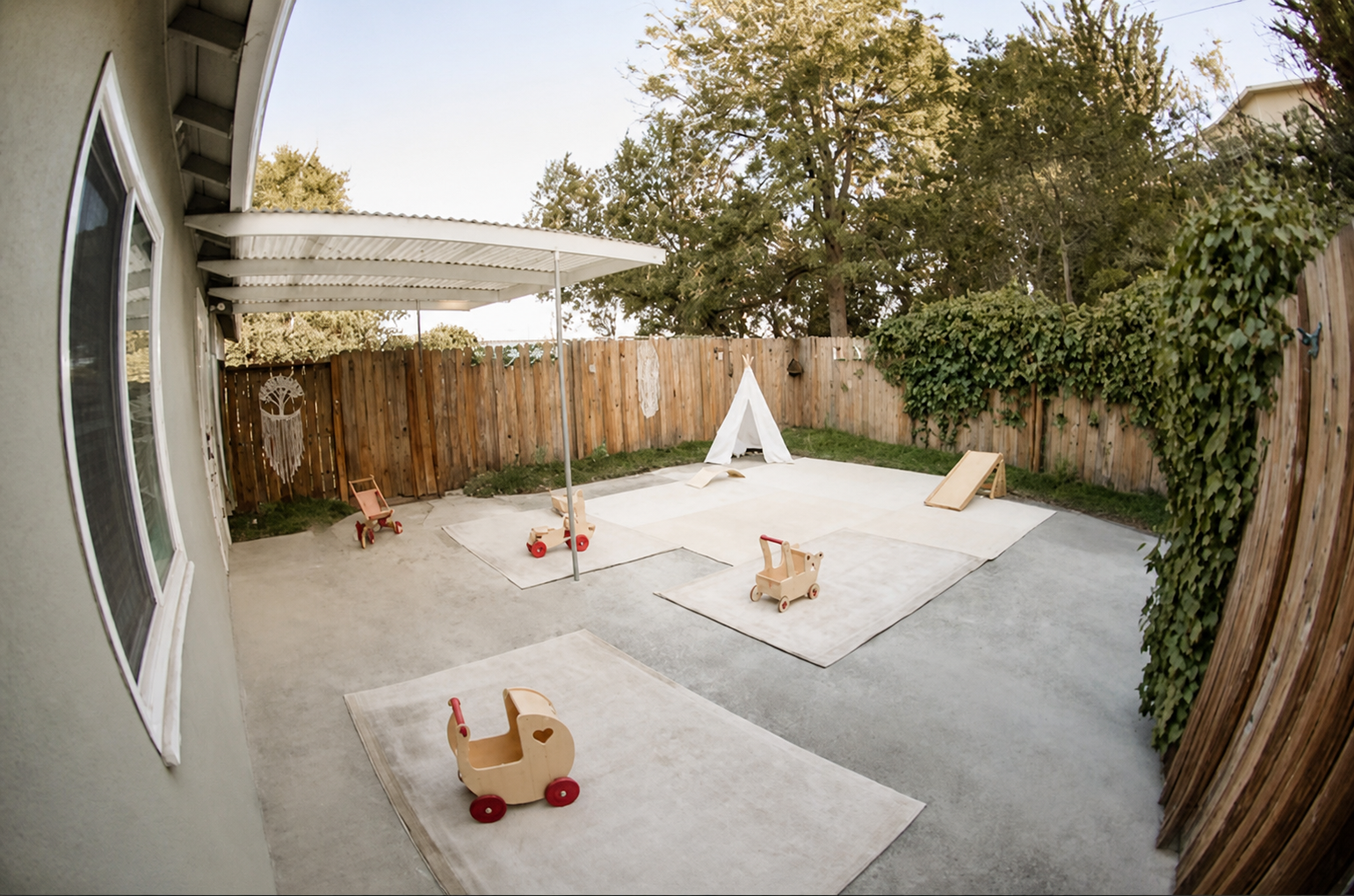 The covered patio with a teepee, play mats, and wooden push carts