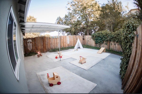The covered patio with a teepee, play mats, and wooden push carts