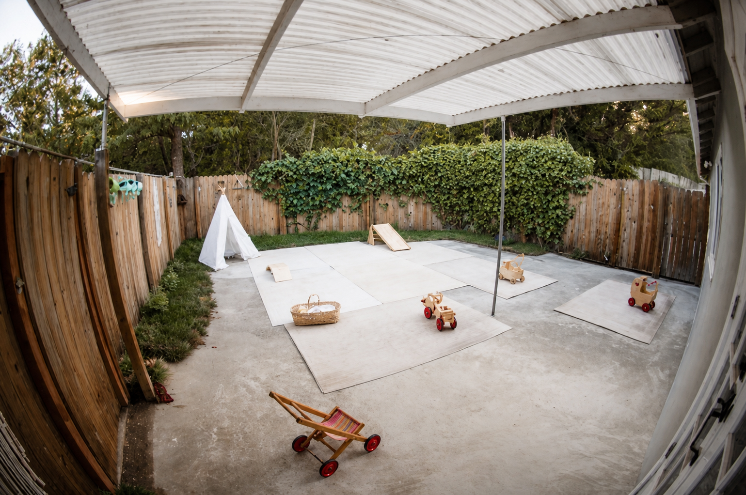 The covered patio play area with a canvas teepee, play mats, and wooden toys