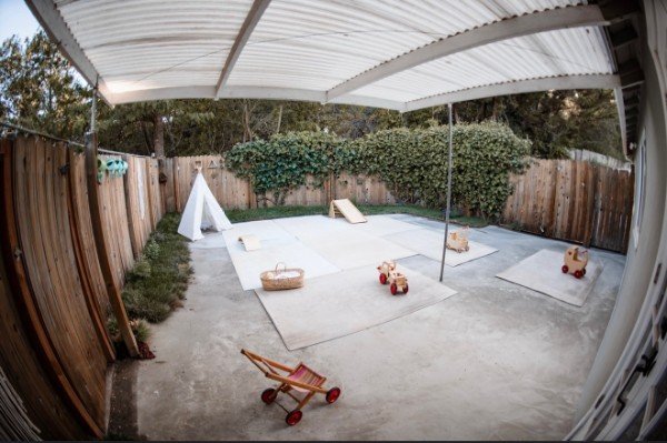The covered patio play area with a canvas teepee, play mats, and wooden toys