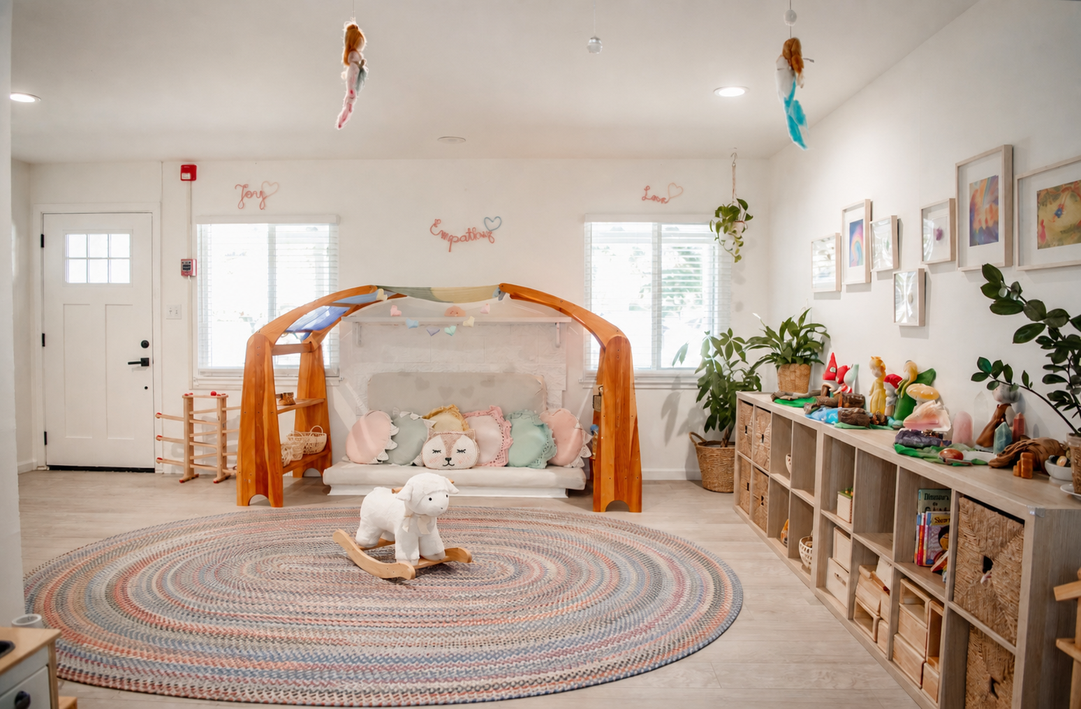 The indoor playroom with a wooden canopy daybed, lamb rocker, and round braided rug