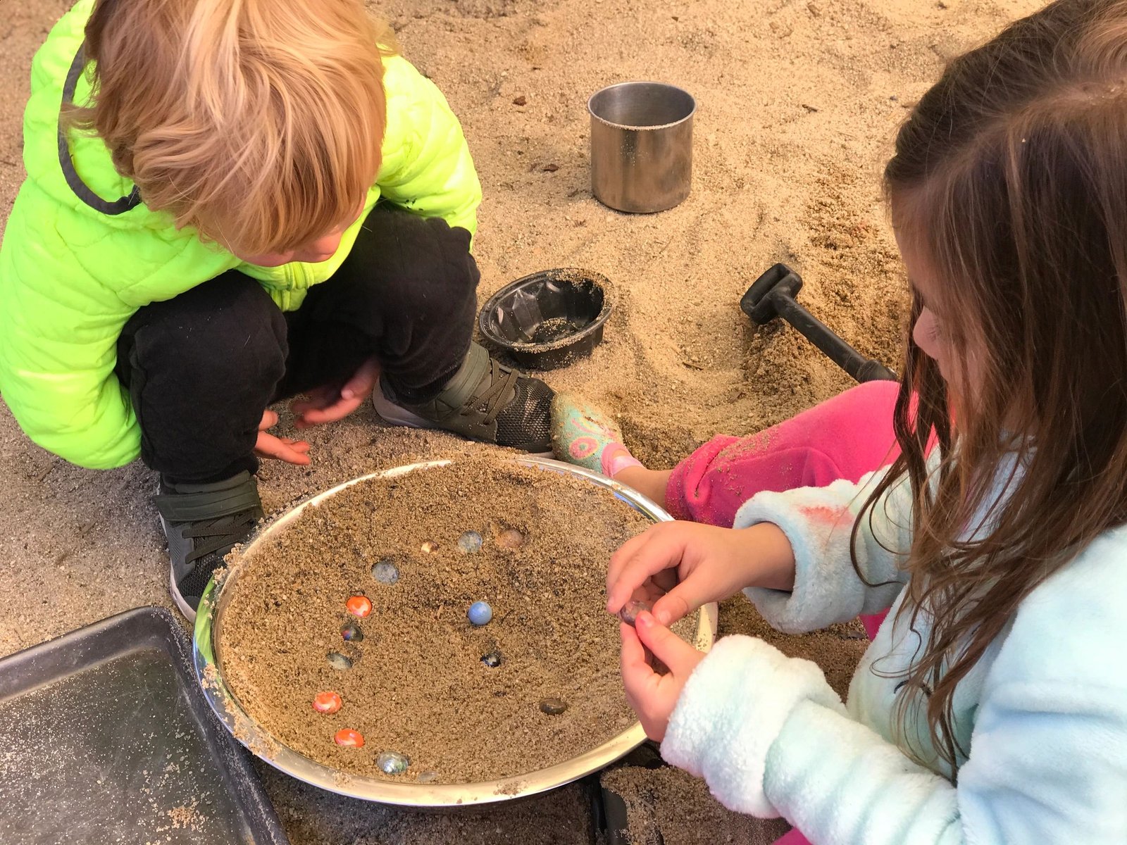 Children sifting for colorful gems in a sand tray