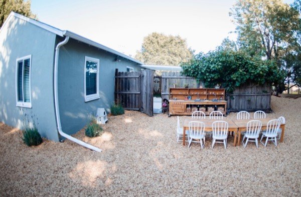 The outdoor play yard with a long wooden table and the mud kitchen along the fence