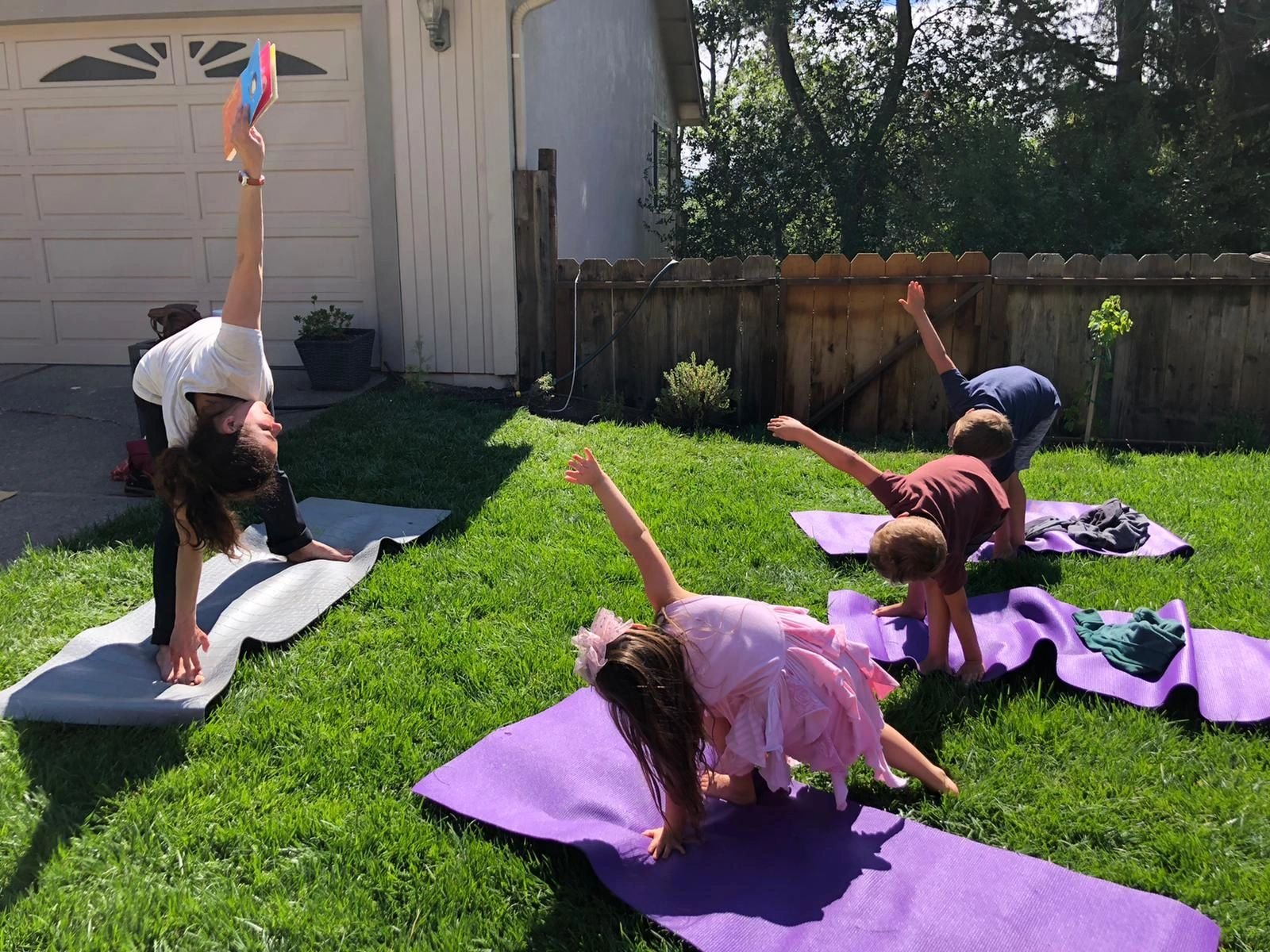 Children doing yoga poses on mats in the garden