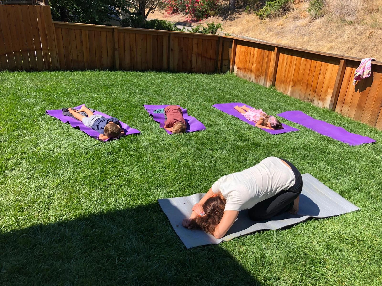 A teacher and children doing yoga together outdoors